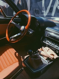 Elegant hands wearing black driving gloves, captured mid-drive with a vintage car interior in warm tones.