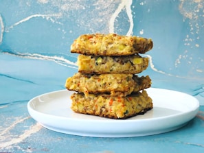 A stack of golden-brown zucchini fritters served with a dollop of lemony yogurt on a white plate