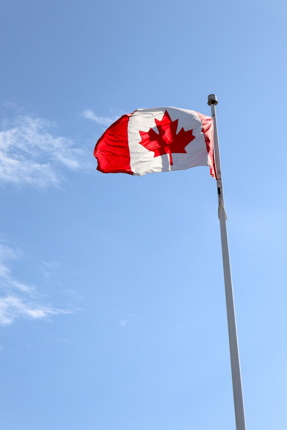 a canadian flag flying high in the sky