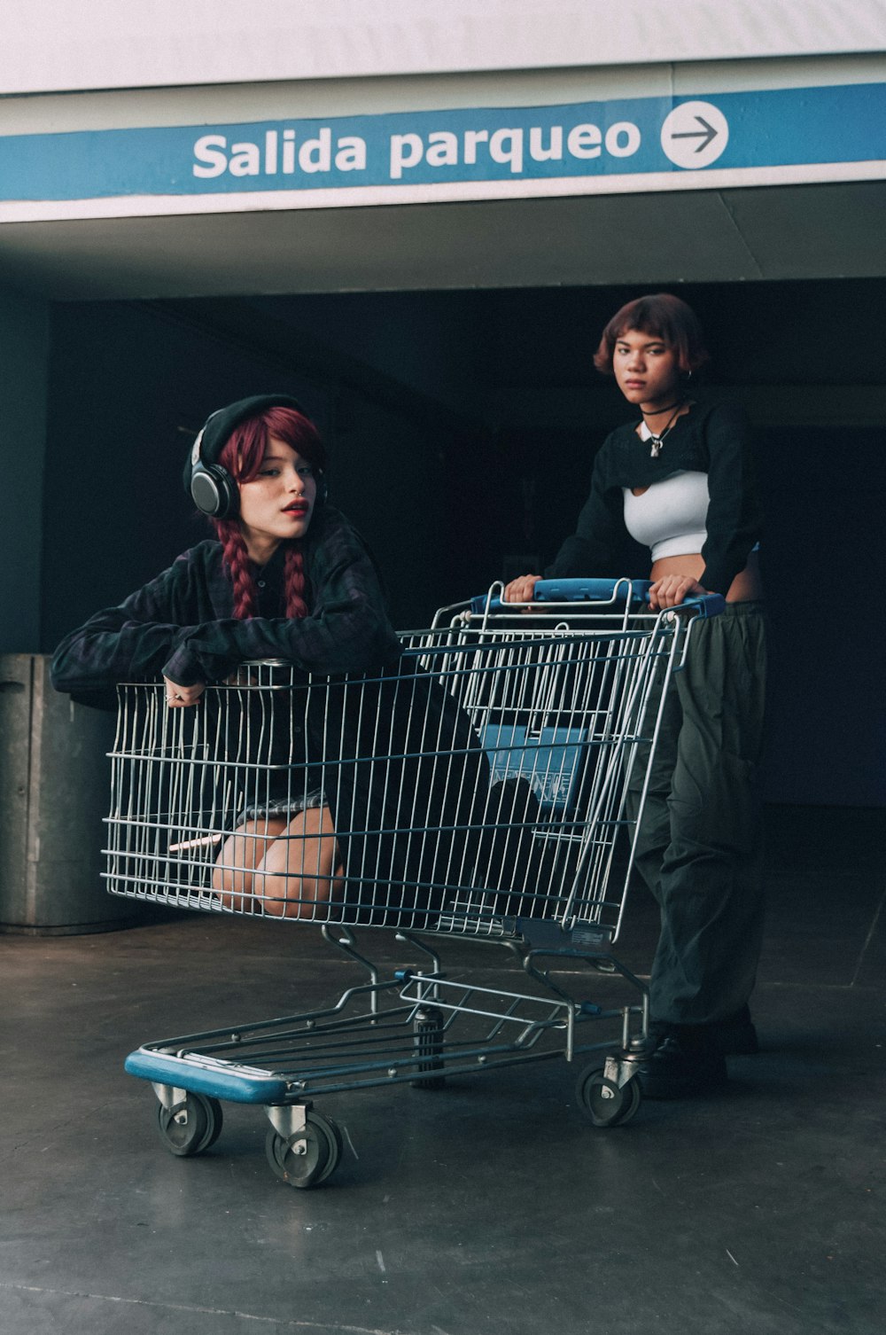 a woman sitting in a shopping cart next to a man