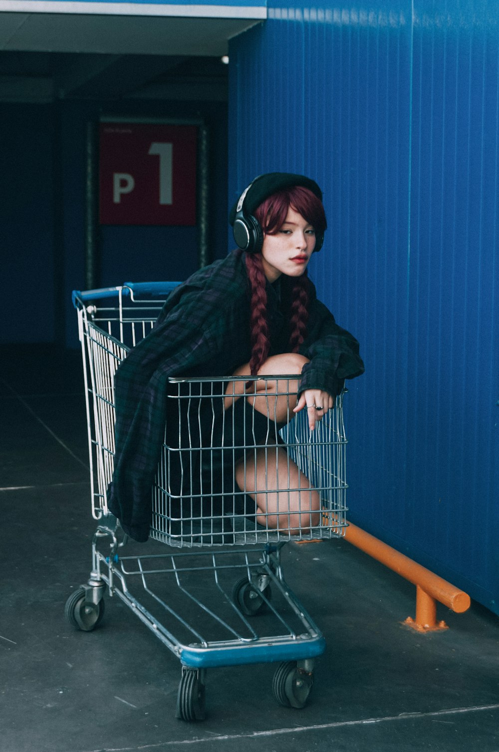 a woman sitting in a shopping cart wearing headphones