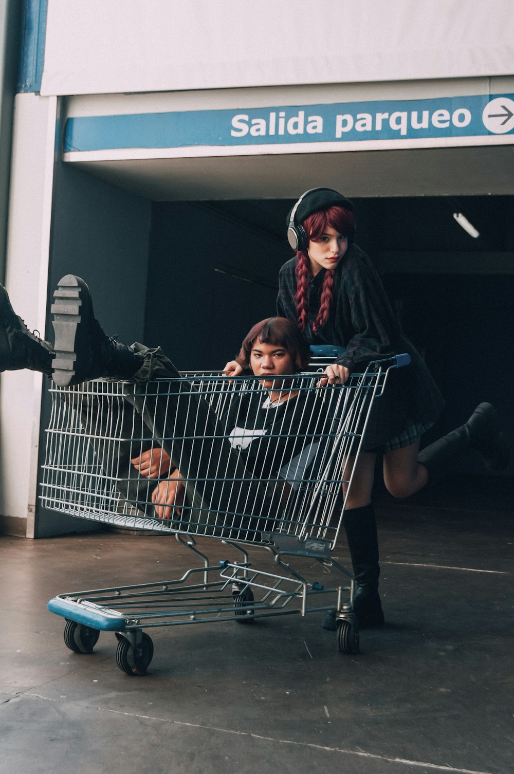 a woman pushing a shopping cart with two children in it