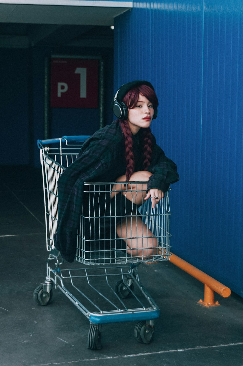a woman with headphones sitting in a shopping cart