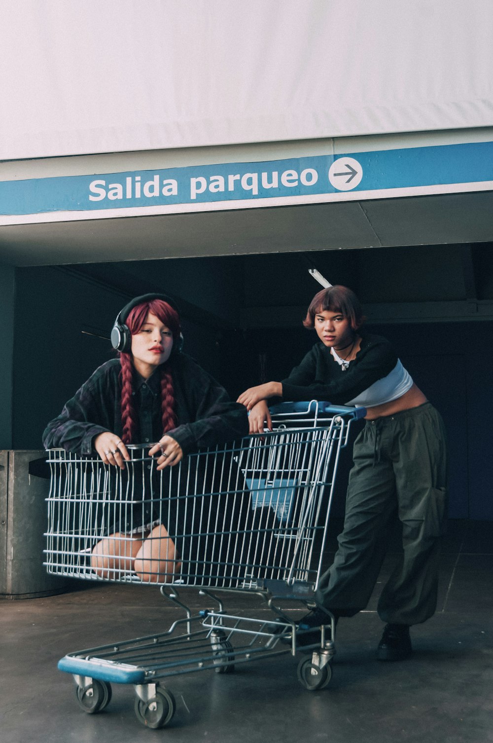 a couple of women standing next to a shopping cart