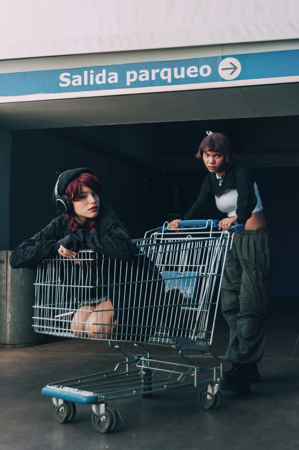 a woman sitting in a shopping cart next to another woman