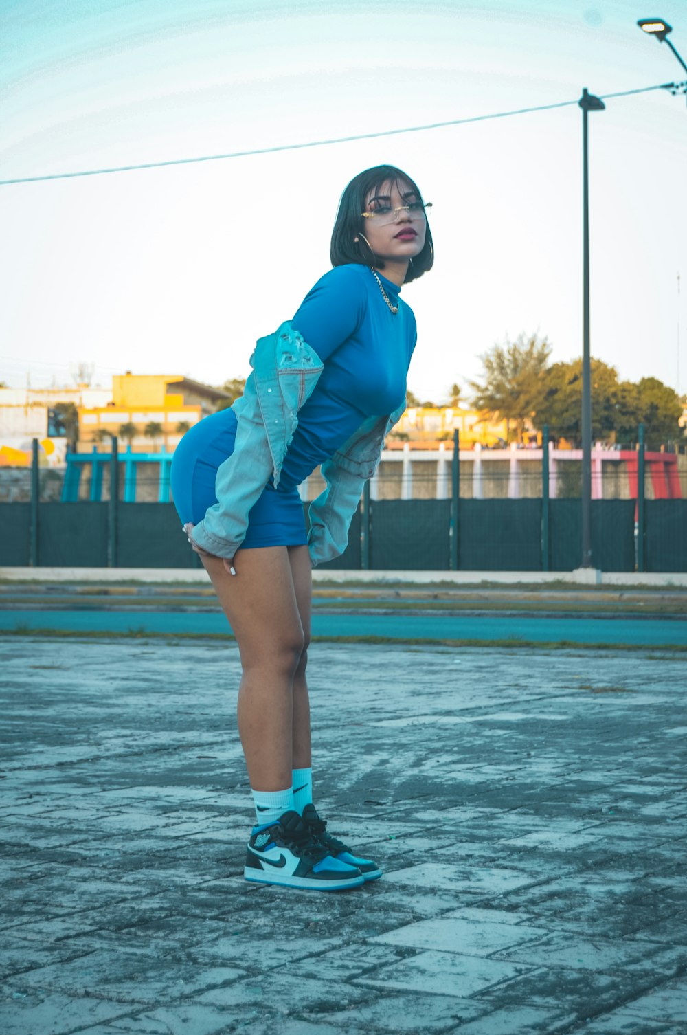 a woman standing in a parking lot with a tennis racket