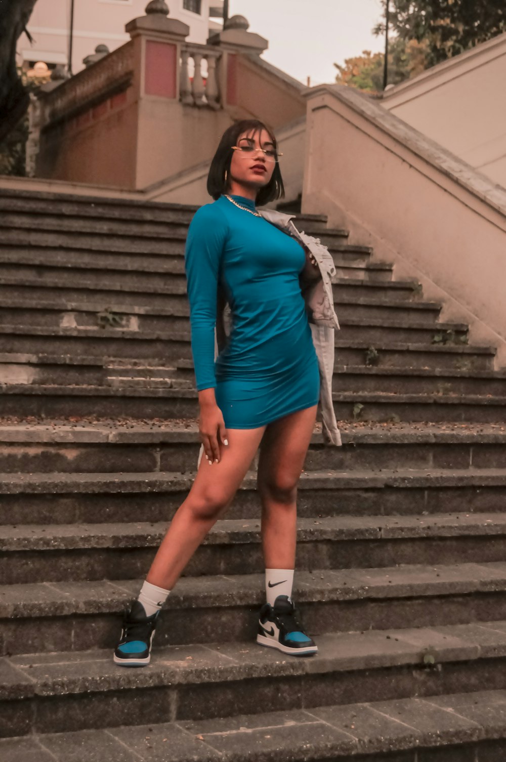 a woman in a blue dress standing on some steps