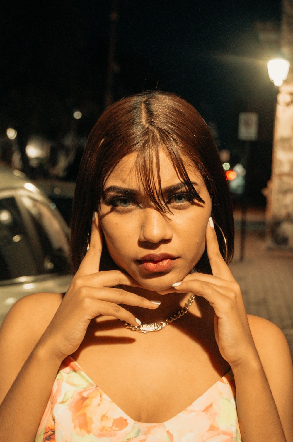 a woman in a floral top is holding her hand to her face