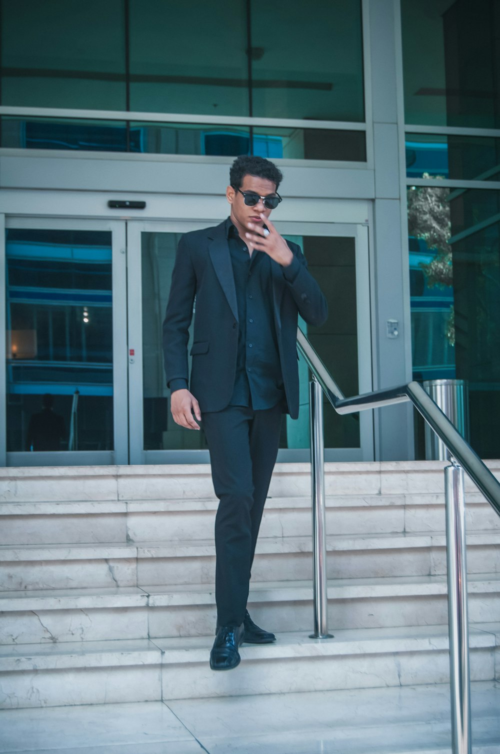 a man in a suit and sunglasses smoking a cigarette