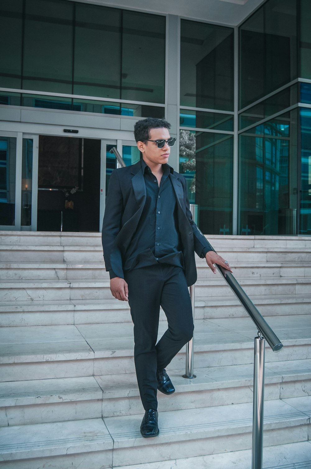 a man in a suit and sunglasses standing on a set of stairs