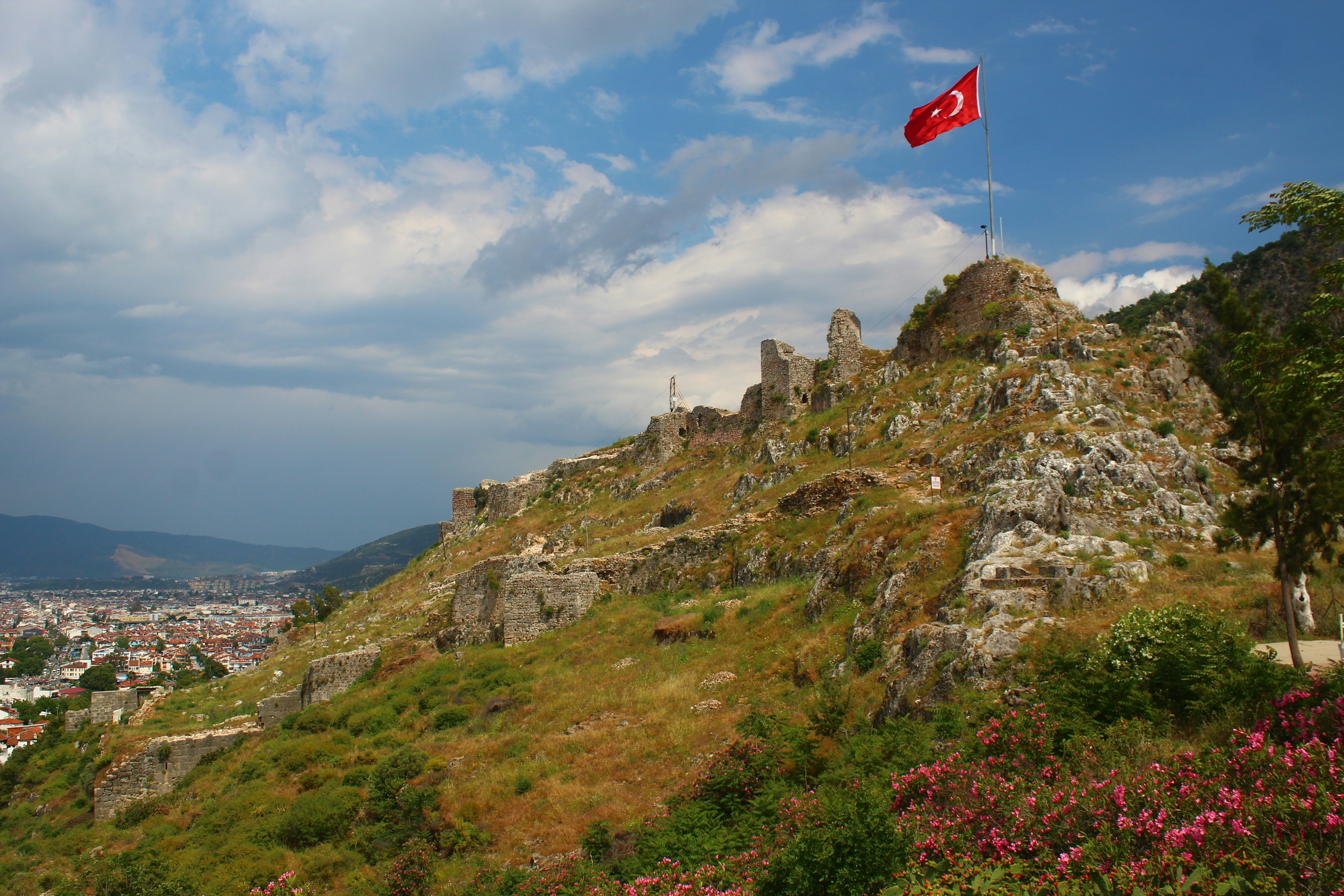 a flag on top of a hill with a city in the background