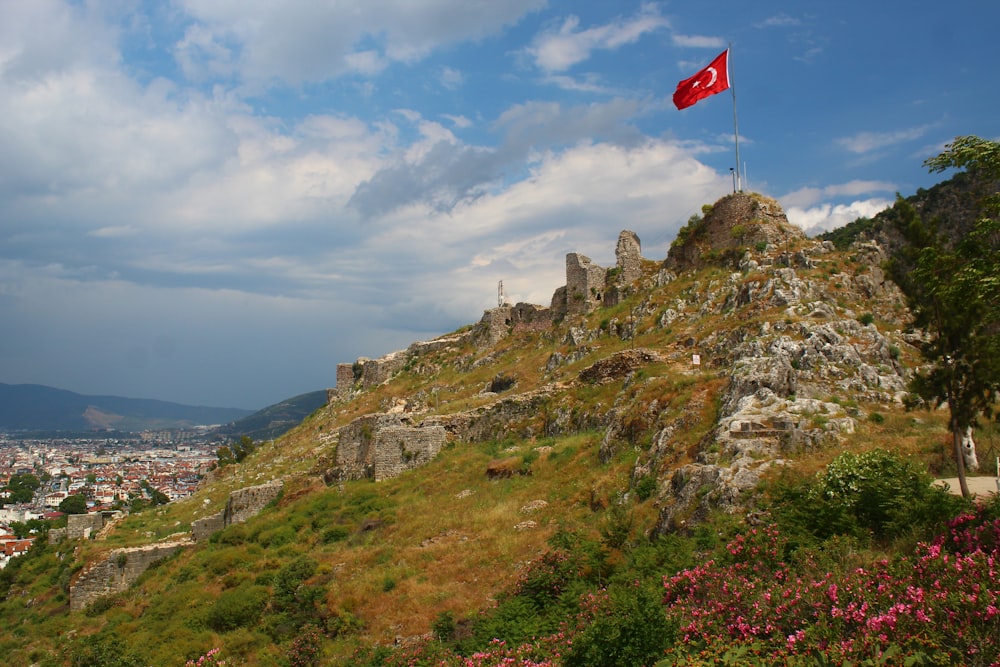 a flag on top of a hill with a city in the background
