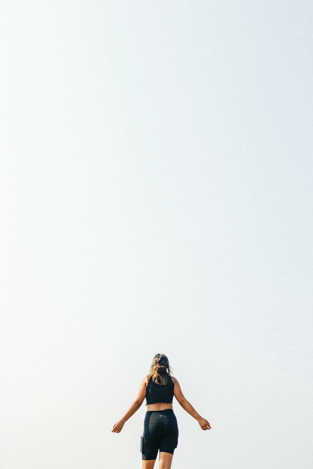 a woman flying a kite on top of a sandy beach