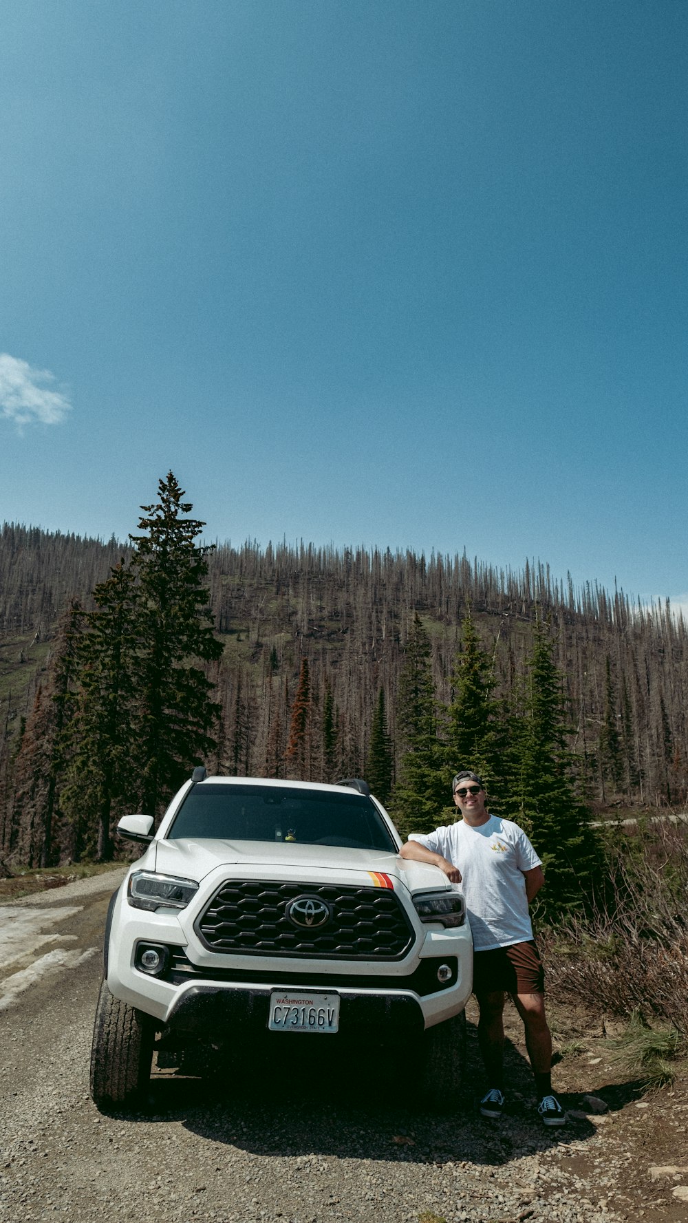 a man standing next to a truck on a dirt road