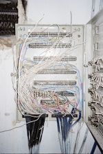 Electrician installing modern electrical panel with blue and yellow cables