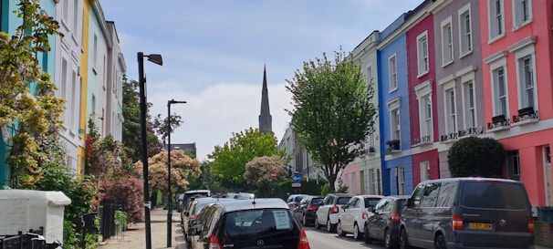 Street view showing a row of medium-standard houses with green and brown facades