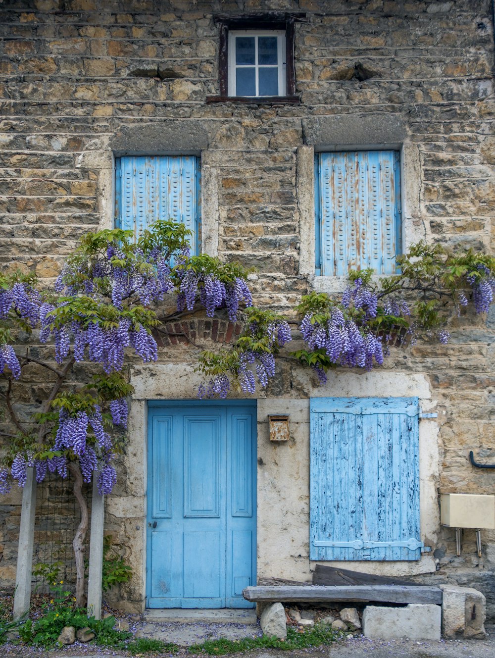 an old building with blue doors and wisters growing on it