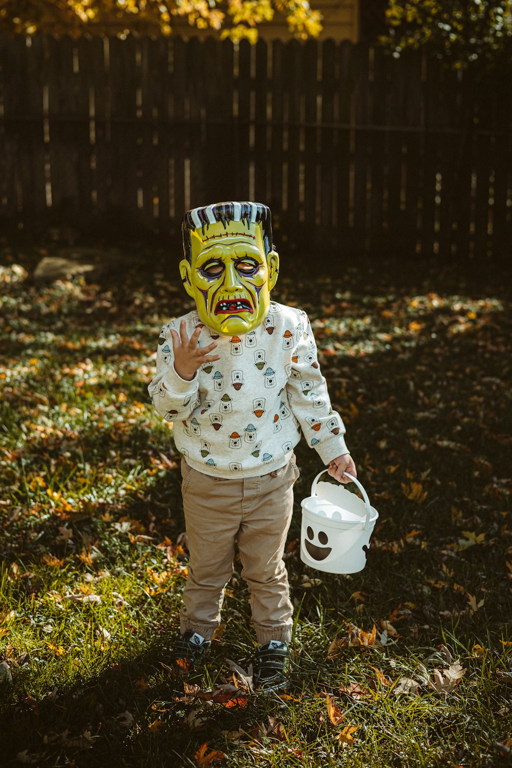 a little boy wearing a mask and holding a bucket