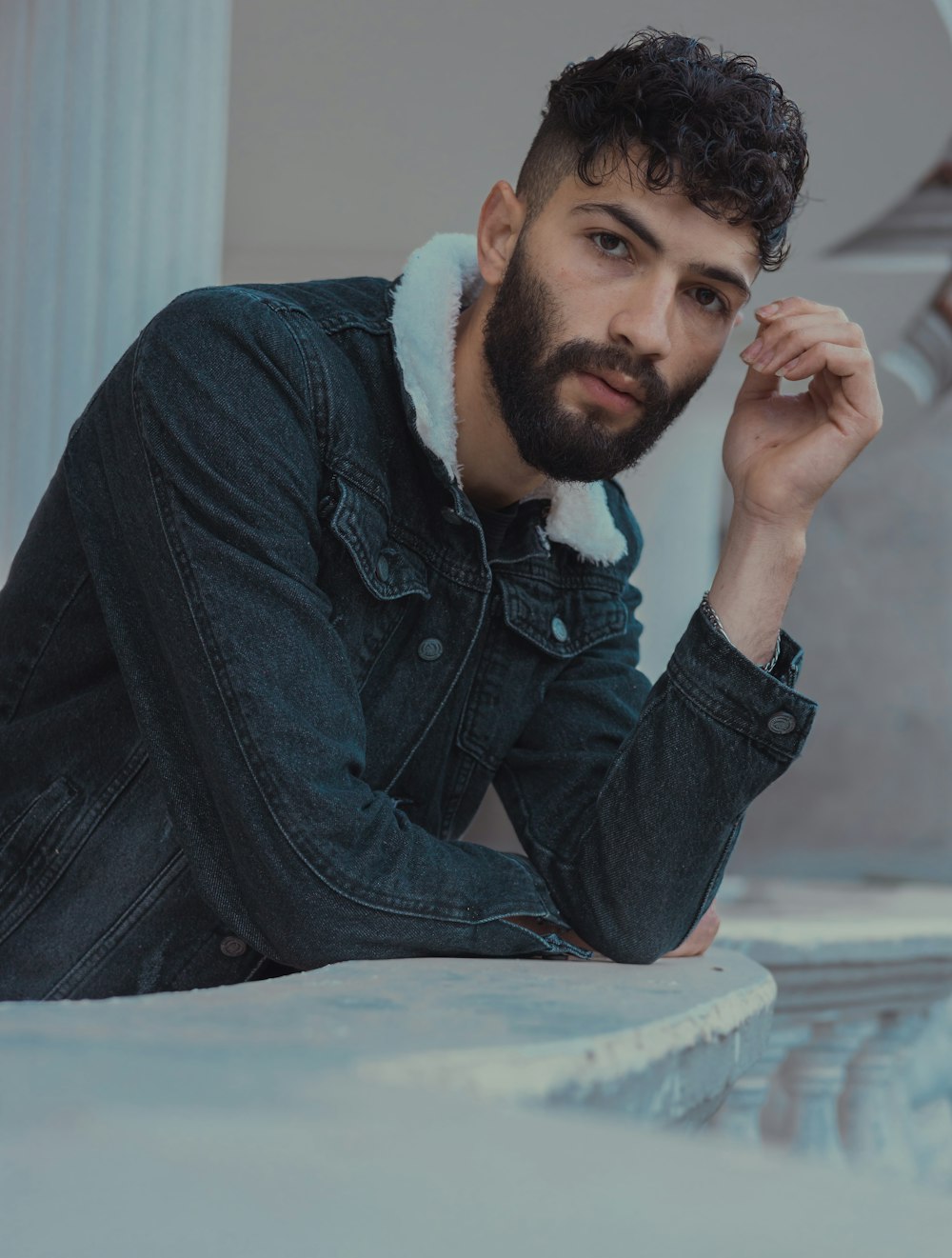 a man with a beard sitting on a ledge