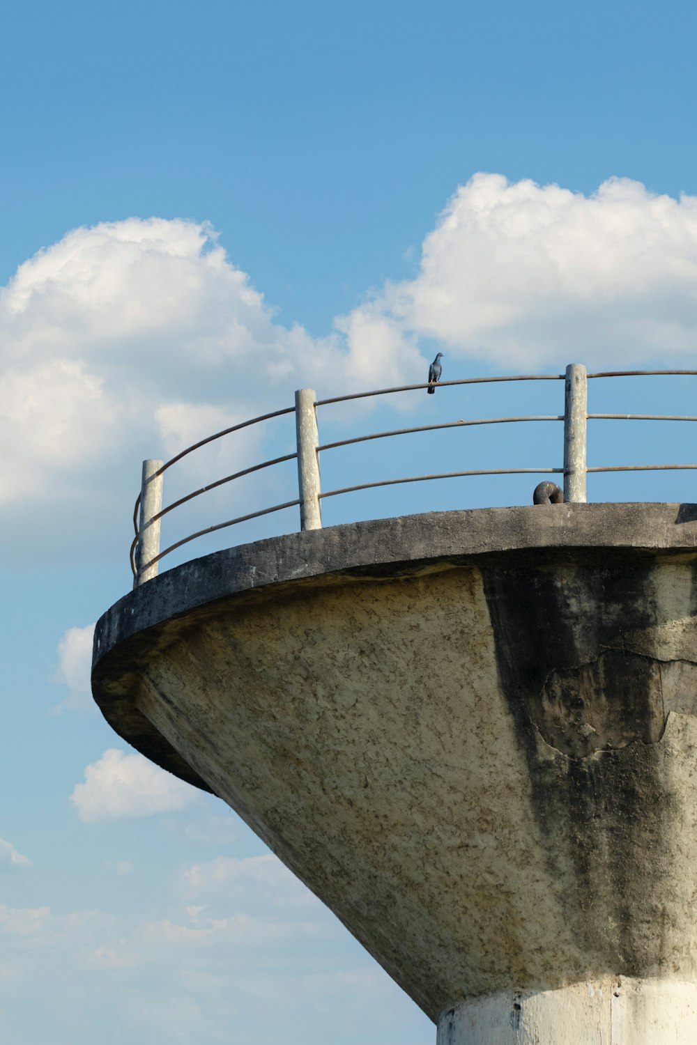 a bird is sitting on the railing of a concrete structure