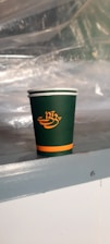 Close-up of a clear polypropylene cup with a vibrant green custom logo printed on it.