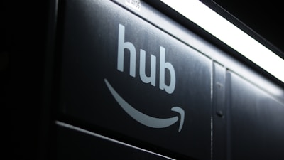 A dark image featuring the word 'hub' and an Amazon smile logo beneath a bright, white fluorescent light strip.