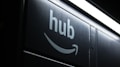 A dark image featuring the word 'hub' and an Amazon smile logo beneath a bright, white fluorescent light strip.