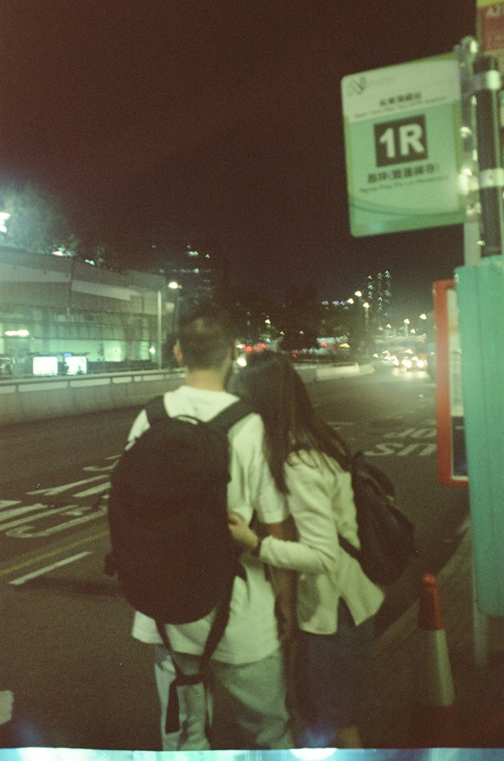 a couple of people walking down a street at night