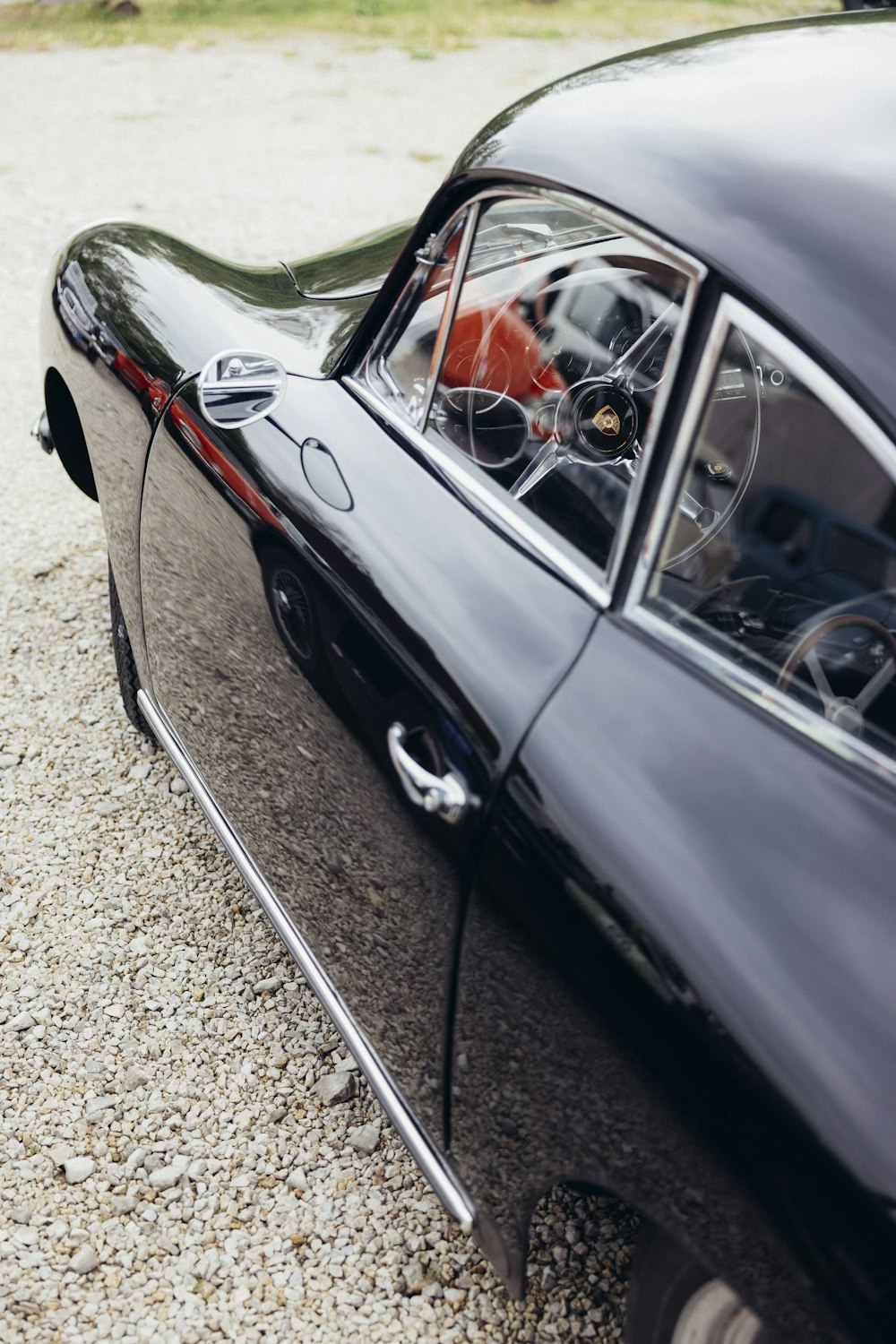 a black car parked on top of a gravel road