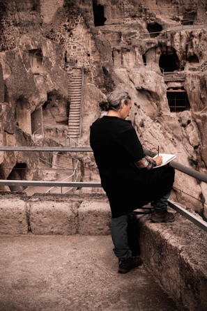An artist sketching the ancient walls of a mountain monastery nestled in the hills.