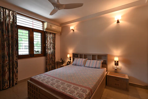 Cozy modern bedroom with dark walls and soft ambient lighting highlighting a plush queen bed.