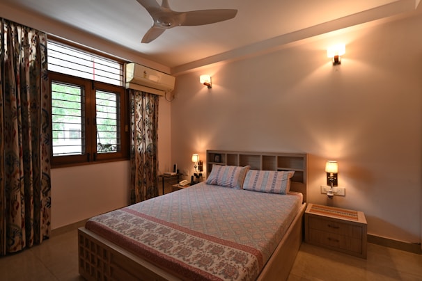 A bright bedroom featuring a queen-size bed with colorful linens.