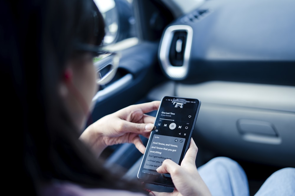 a woman sitting in a car holding a cell phone