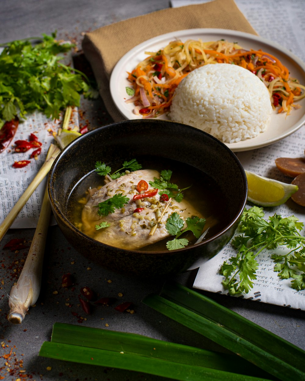 a table topped with a bowl of soup and a plate of rice