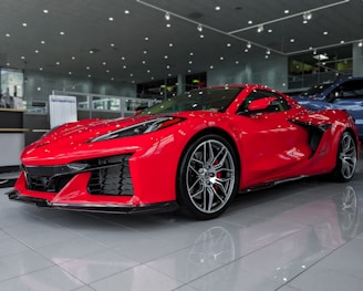 Front view of a sleek red new car displayed in a modern showroom
