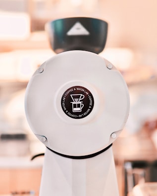 Close-up of coffee grounds next to a manual grinder on a beige background.