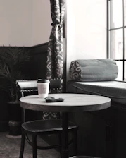 A cozy cafe corner with warm lighting, a steaming cup of coffee, and a meditation cushion nearby.
