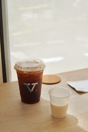 A steaming cup of cold brew coffee with ice cubes on a sunny table.