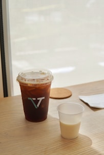 A steaming cup of cold brew coffee with ice cubes on a sunny table.