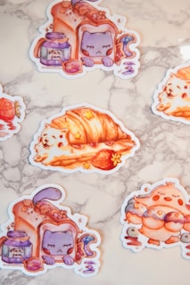 Illustrated stickers featuring whimsical animal-themed pastries and jars labeled 'star jam.' One is a purple cat inside a slice of bread, another is a roll with a white dog, and a third depicts an orange bird with blueberry and crescent moon elements.