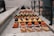 An assortment of colorful pastries and desserts are neatly arranged on a marble countertop. The selection includes pieces of cheesecake, orange and yellow square-shaped pastries, and beautifully decorated eclairs. Bright colors contrast with the soft, muted tones of the counter and background.