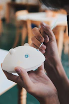 Artisan carefully painting finishing touches on a custom 3D printed model in a bright studio.