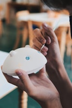 Close-up of hands painting a cheeky boob pot with bright colors and care.