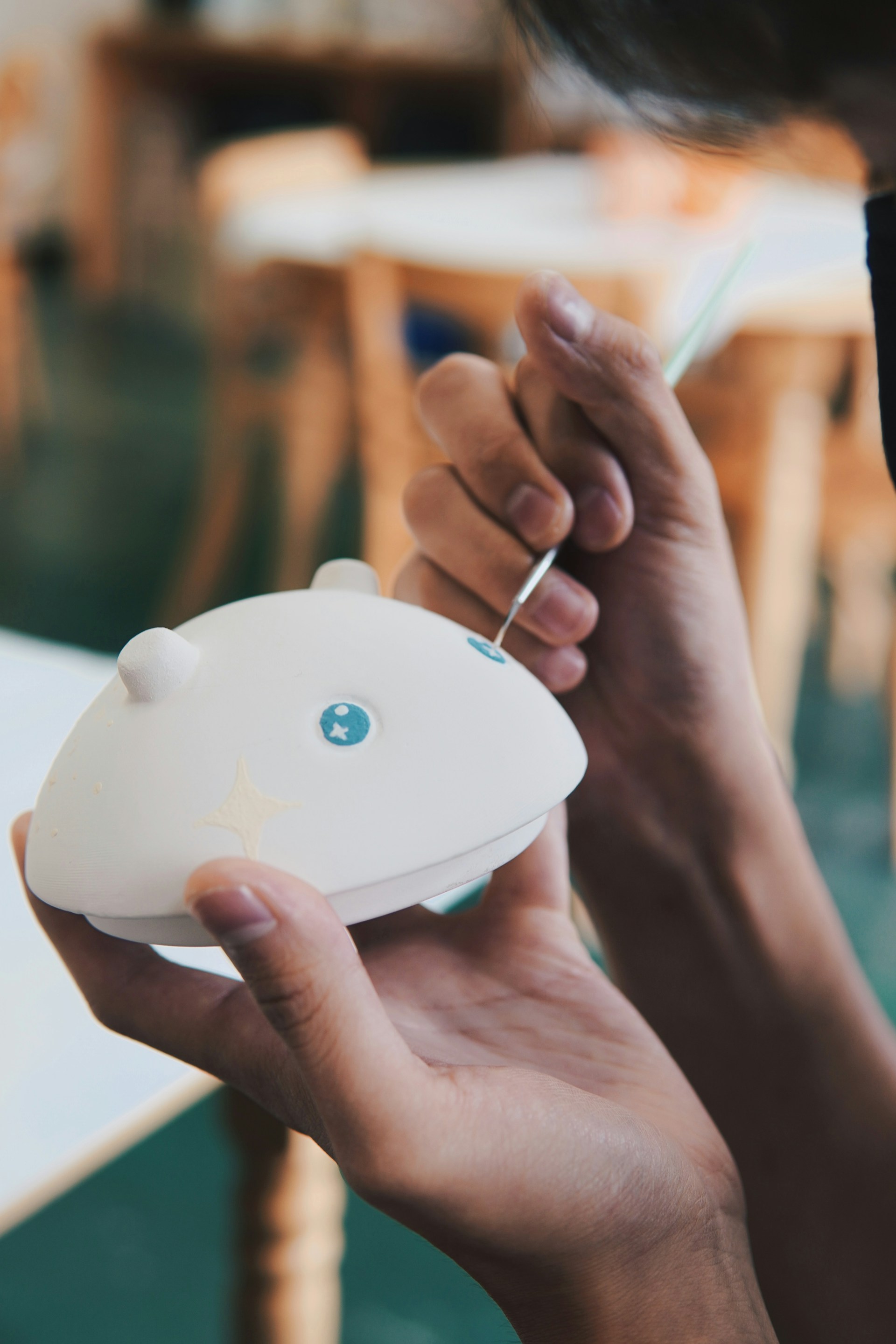 Hands carefully applying finishing touches to a futuristic art object, with tools and materials arranged neatly on a clean, reflective surface.