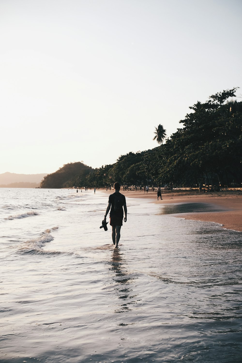 a man walking along a beach next to the ocean