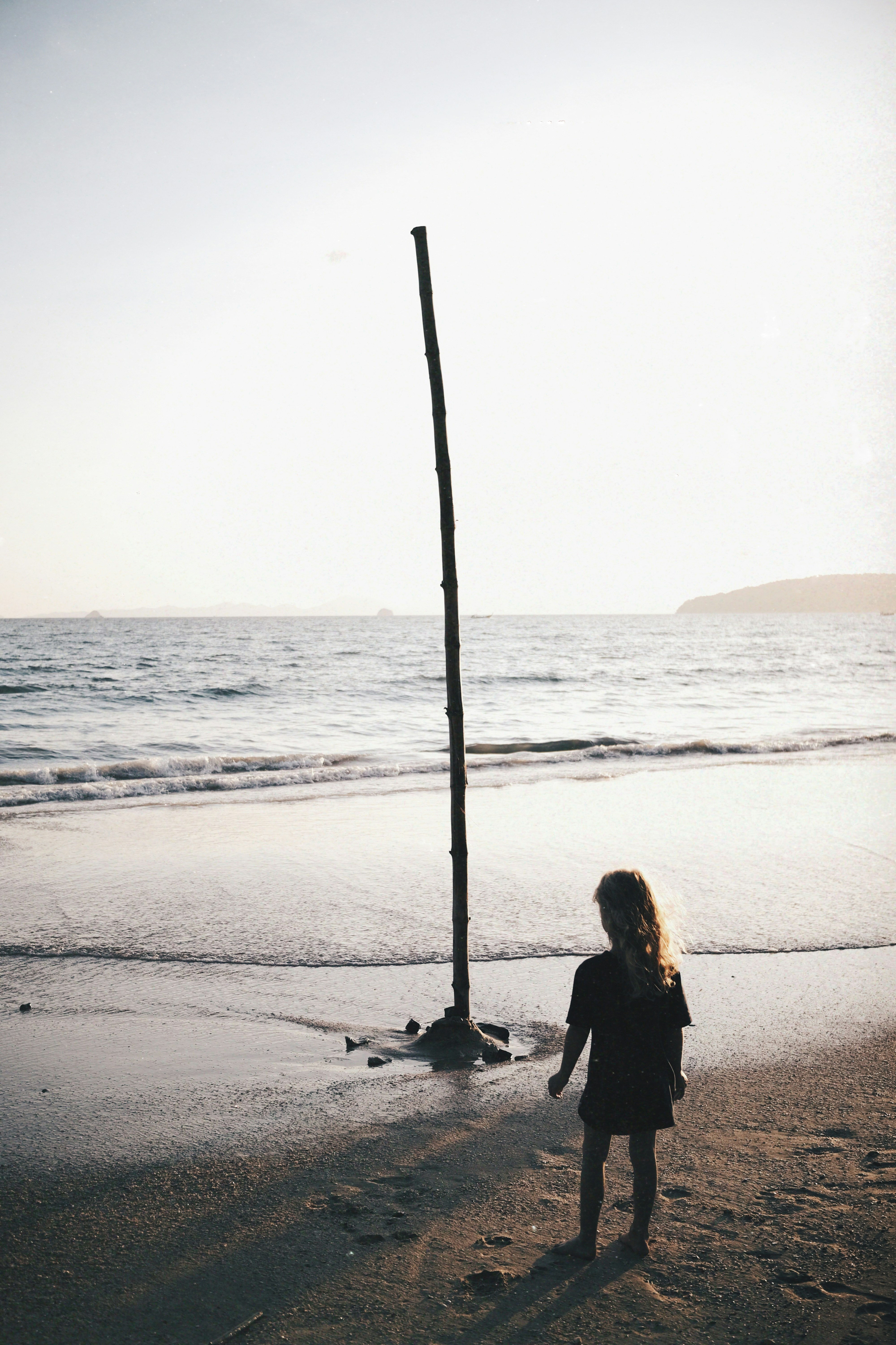 A woman standing on top of a sandy beach next to the ocean photo – Free ...
