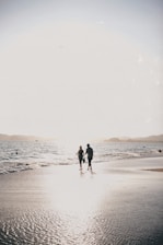A couple holding hands on a beach at sunset, symbolizing a romantic honeymoon trip.