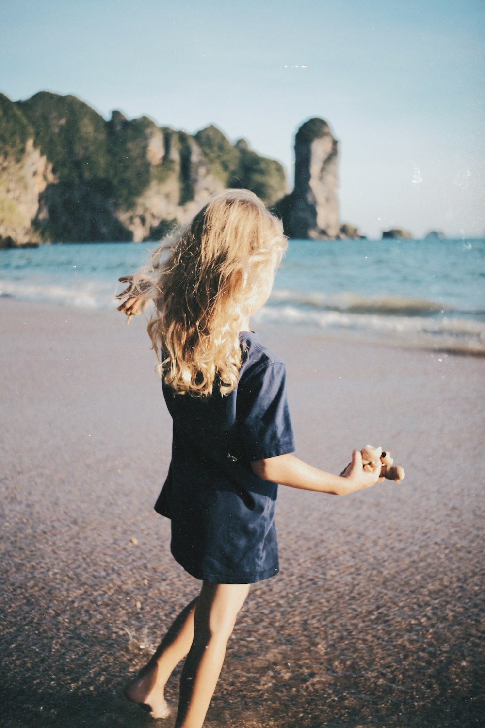 a woman walking on a beach next to the ocean