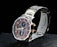 A sleek wristwatch with a stainless steel band featuring gold accents. The watch face combines dark and light elements in a sophisticated design, showcasing several subdials with gold hands and markers. The brand name is visible on the face, adding to its luxurious appeal.