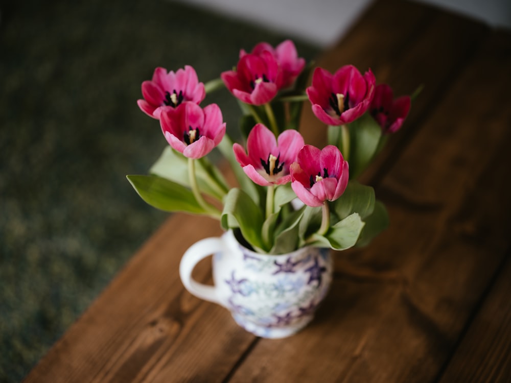 a vase filled with pink flowers on top of a wooden table